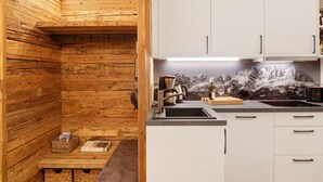 A kitchen with wooden walls, white cabinets, a stainless steel sink, and a mountain view mural. - Apartment 'Panorama Chalets Am Pass Thurn' with Mountain View, Private Terrace and Wi-Fi (Mittersill)