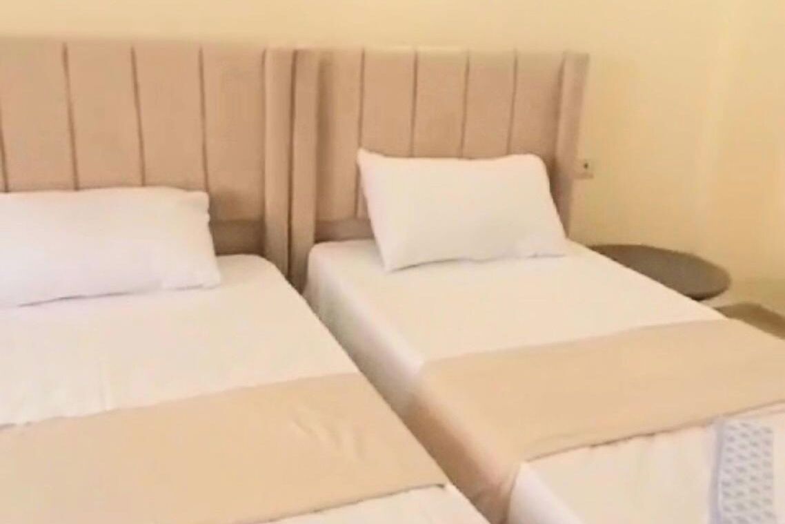 Ein Hotelzimmer mit zwei Betten, jeweils mit Kopfteil und weißer Bettwäsche.