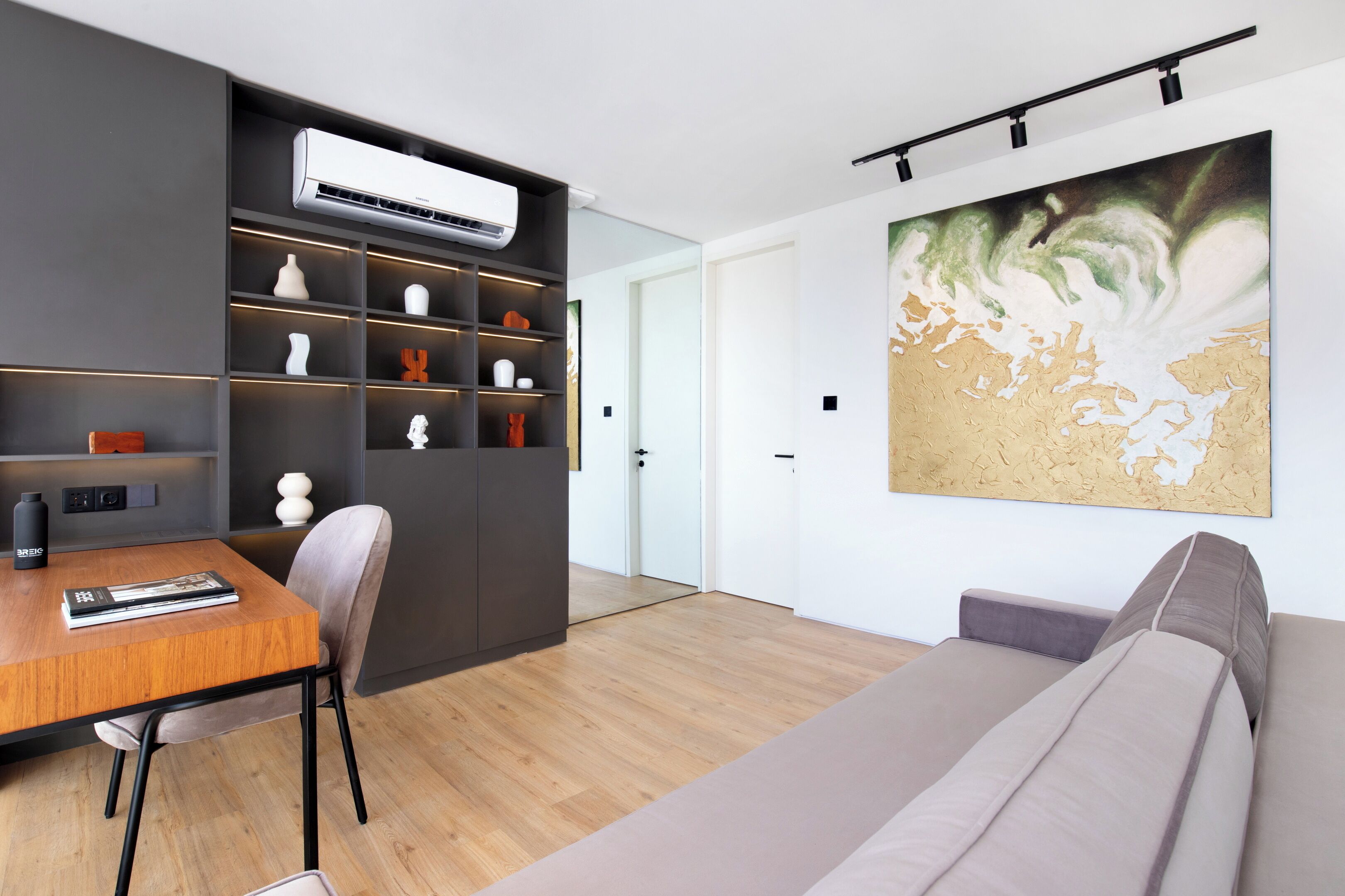 A modern living room with a wooden dining table, a sofa, and a large abstract painting on the wall.