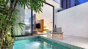Ein moderner Poolbereich im Innenbereich mit einer klaren Glasscheibe, einem Holzstuhl und einer weißen Bank.