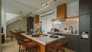 Eine moderne Küche mit Kochinsel, Barhocker und einer Treppe zu einer weiteren Ebene.