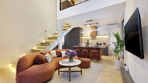 Ein modernes Wohnzimmer mit einer gebogenen Couch, einem Couchtisch und einem an der Wand montierten Fernseher.