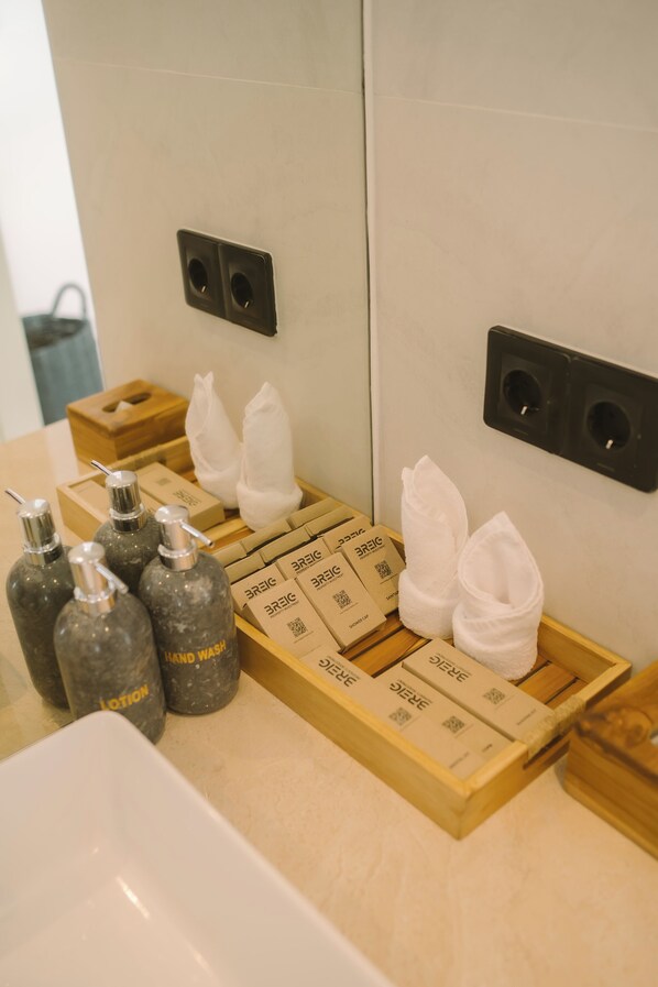 A bathroom with a sink, hand wash bottles, and a wooden tray with towels and toiletries. - The Oasis II Townhouses by BREIG (Canggu)