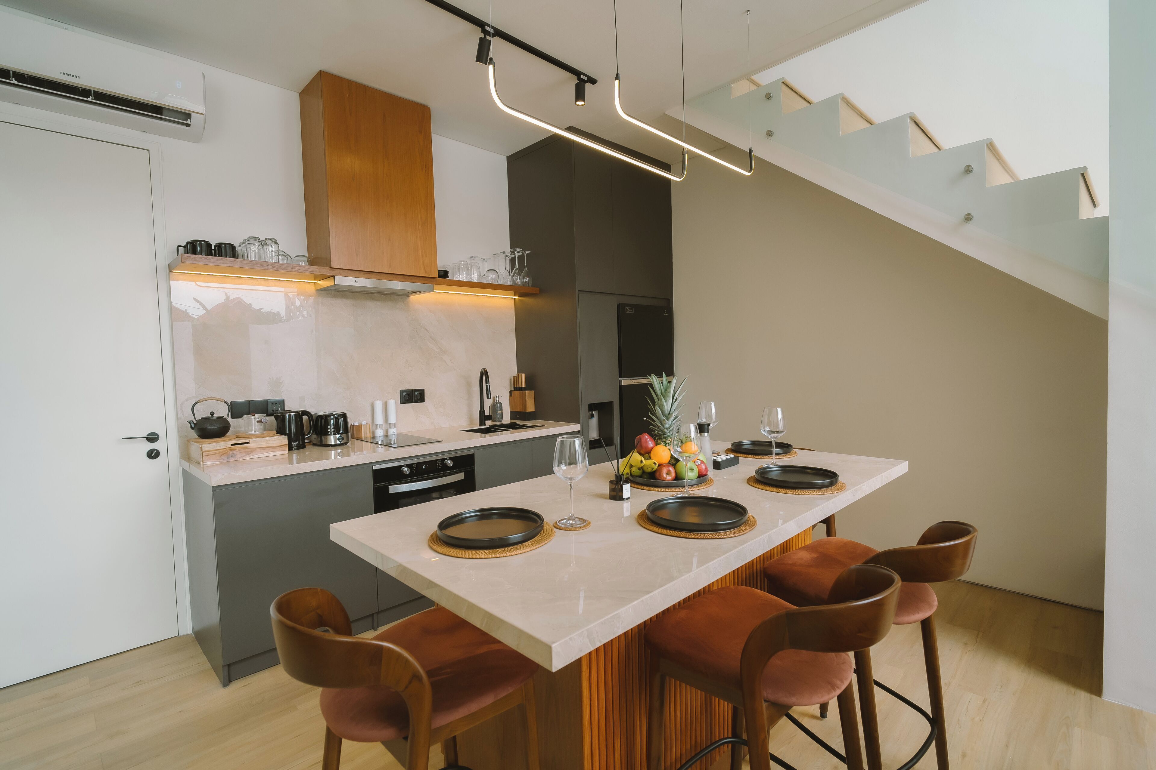 Una cucina moderna con isola centrale, sgabelli da bar e una scala.
