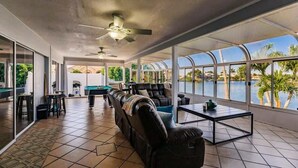 A spacious indoor area with a pool view, a ceiling fan, and a seating area with a coffee table.