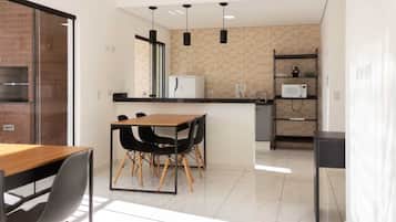 A modern kitchen with a dining area, featuring a wooden table, black chairs, and a built-in microwave.