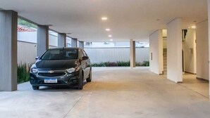 A covered parking area with a car parked in the foreground. - Sapucaia Flat (Santa Rita do Sapucai)