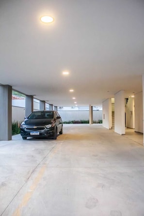 Uma área de estacionamento coberta com um carro estacionado em primeiro plano.