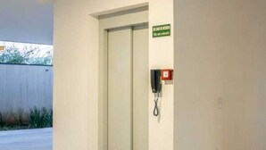 A hotel entrance with a door, a phone, and a sign. - Sapucaia Flat (Santa Rita do Sapucai)