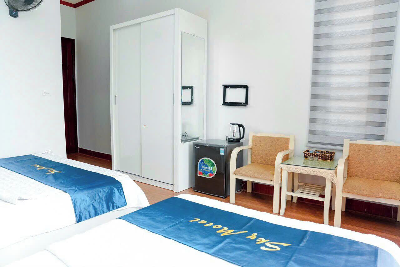 Une chambre d’hôtel avec deux lits, un bureau, une chaise, une machine à café et une armoire.