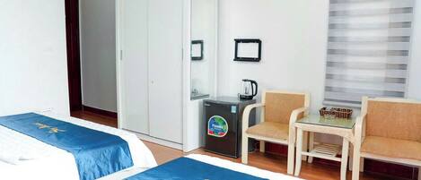 Une chambre d’hôtel avec deux lits, un bureau, une chaise, une machine à café et une armoire.