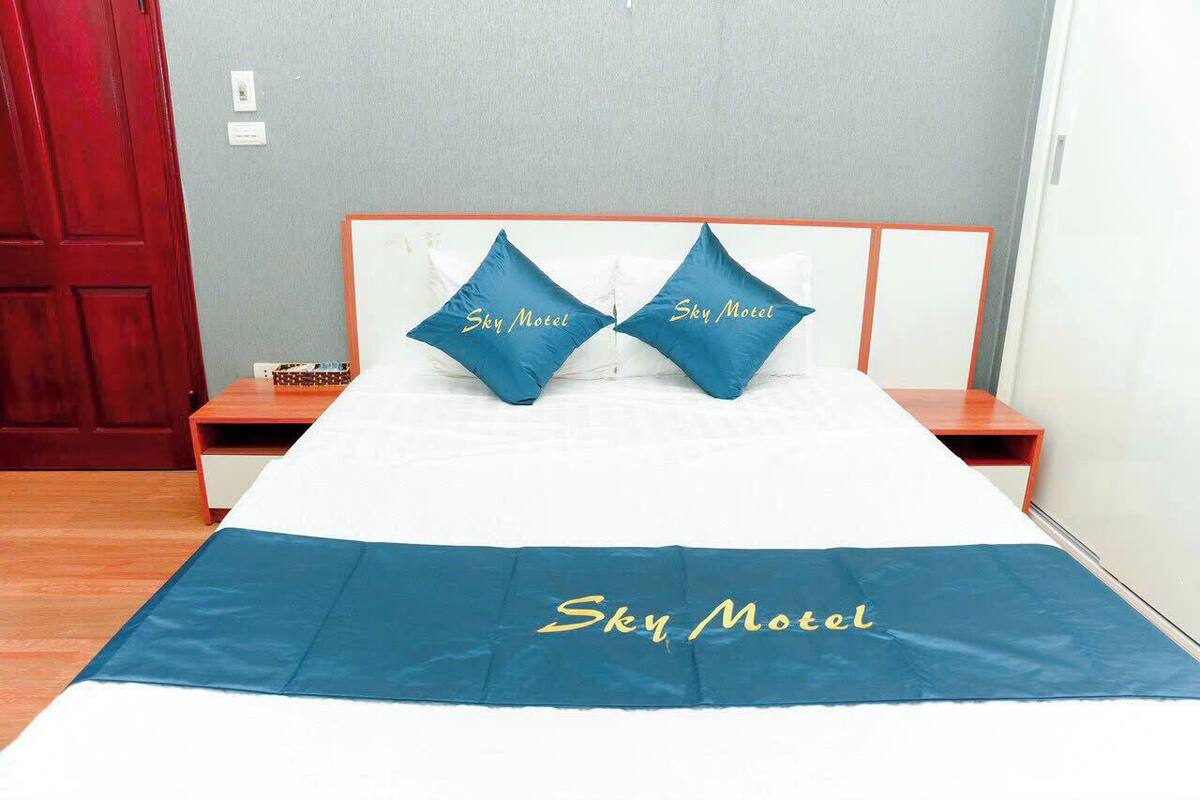 A bed with a blue bedspread and pillows labeled "Sky Motel."