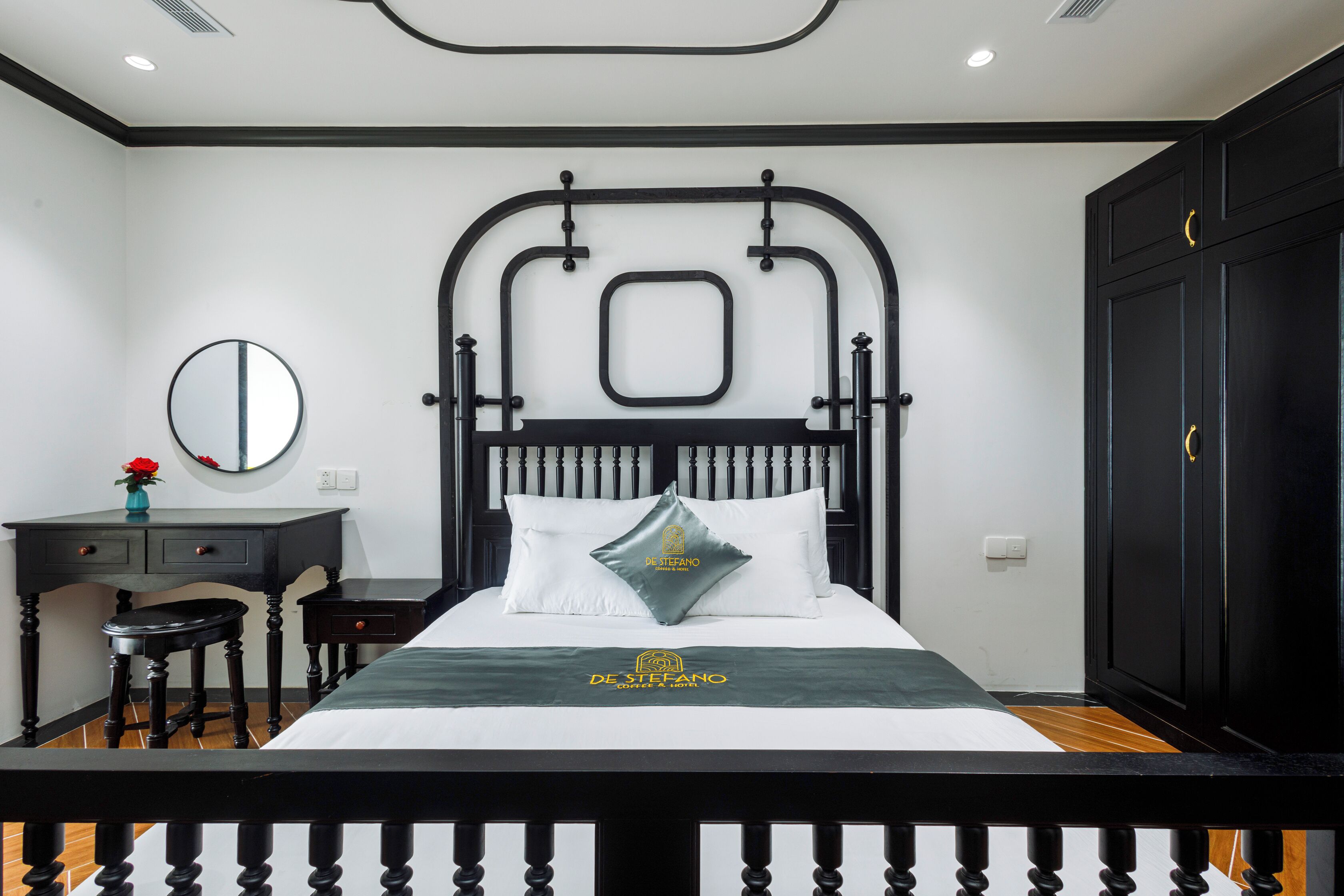 A neatly arranged bedroom with a bed, a dresser, a mirror, and a desk.