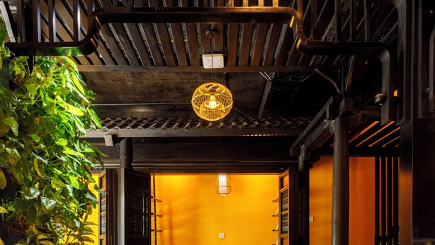 A traditional interior with a wooden ceiling, a dining area with a table and chairs, and a potted plant. - De Stefano Coffee and Hotel (Phu Quoc)