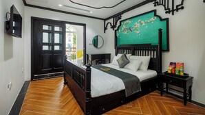 A bedroom with a bed, a nightstand, a mirror, and a green wall decoration. - De Stefano Coffee and Hotel (Phu Quoc)