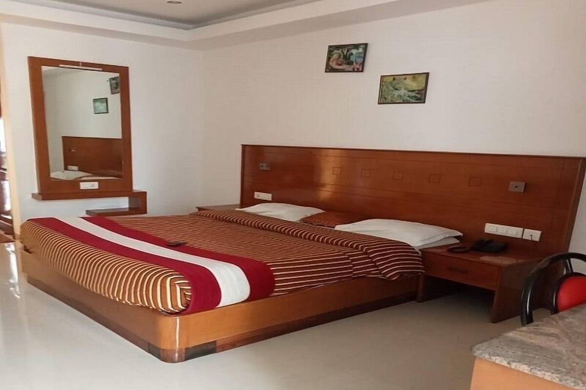 Ein modernes Hotelzimmer mit einem großen Bett, einem Nachttisch, einem Spiegel und zwei Wandbildern.