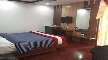A hotel room with a bed, a desk, a chair, a television, and a mirror.