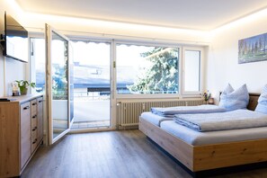 Ein Schlafzimmer mit einem hölzernen Bett, einem Schreibtisch und einer Glastür zum Balkon.
