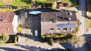 Ein Luftbild eines Parkplatzes mit einem Gebäude, das ein schräges Dach und viele Fenster hat.