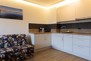 A compact kitchen with white cabinets, a wooden countertop, a coffee maker, and a sink.