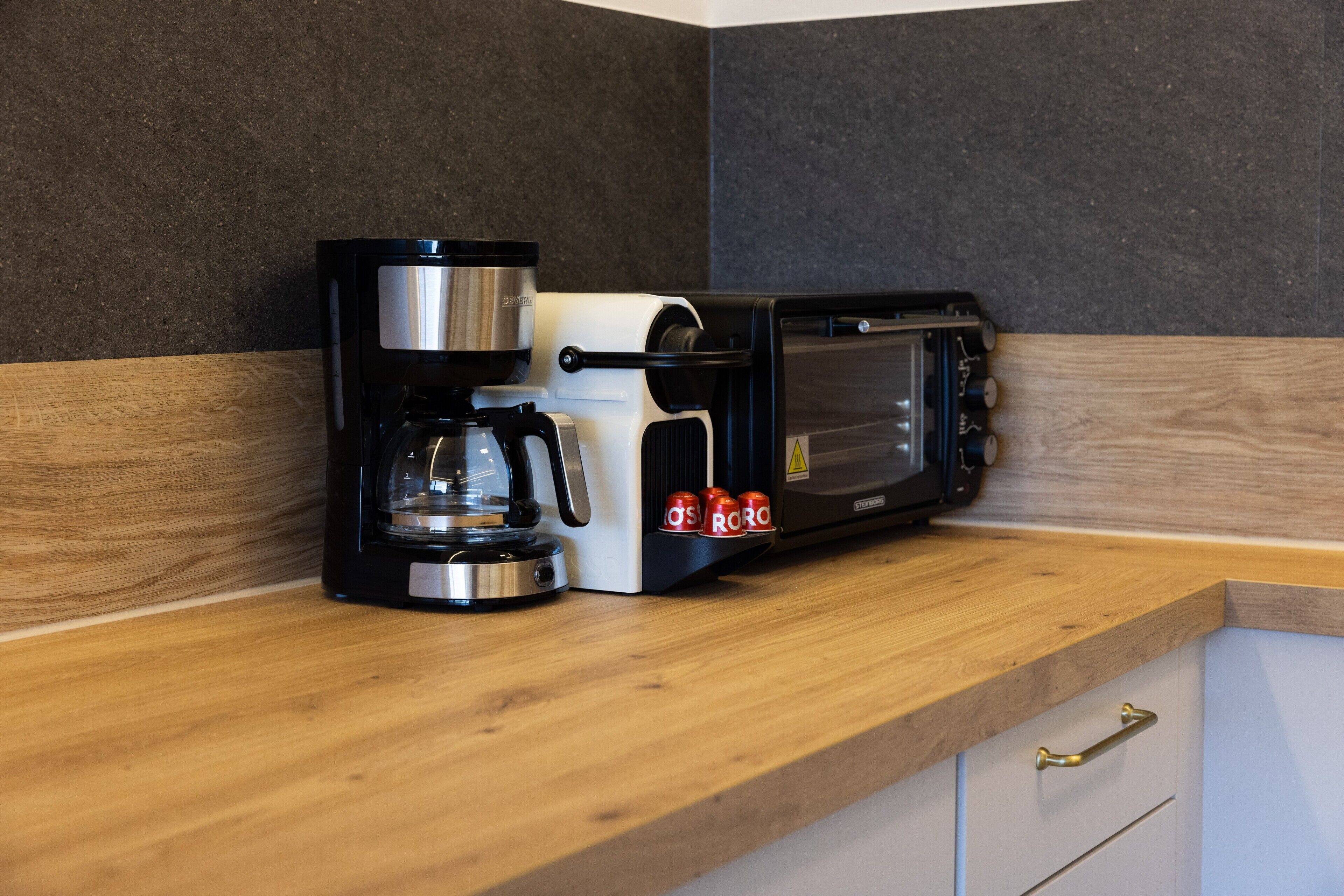 Una cocina con cafetera, tostadora y microondas sobre una encimera de madera.