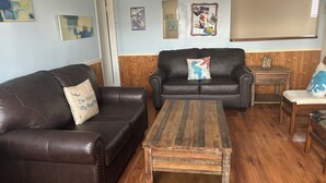 A living room with two leather sofas, a wooden coffee table, and a wooden side table.