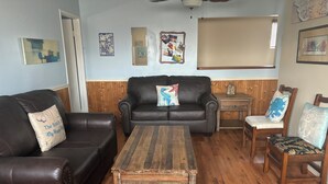 A living room with a brown leather couch, a wooden coffee table, and a wooden side table.