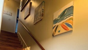 A wooden staircase with white walls and a painting of a beach scene.