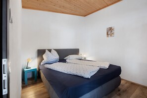 Ett sovrum med en säng, sängbord, en lampa och en liten väggdekoration.