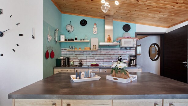 A modern kitchen with a wooden ceiling, a large island, and various kitchen appliances.