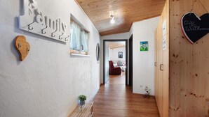A hallway with wooden flooring, a bench, a heart-shaped sign, and a wall-mounted light fixture.