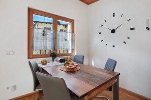 En matplats med ett träbord, stolar, en klocka och ett fönster med gardiner.