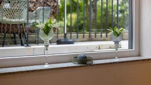 Deux vases en verre ornés de fleurs sont posés sur un rebord de fenêtre.