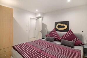 A bedroom with a bed, pillows, a wardrobe, and a wall art piece.