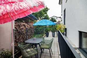 A patio with a table and chairs, a blue umbrella, and a pink umbrella.