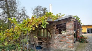 Une construction en briques avec une cheminée, une table en bois et une balançoire faite d’un pneu.
