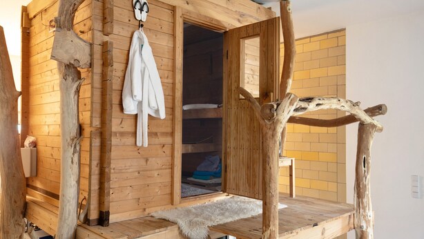 Une cabane en bois dotée d’un sauna intégré, d’un banc et d’un porte-serviettes suspendu.