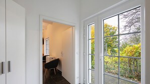 Un couloir avec une porte donnant sur une pièce d’où l’on peut admirer la vue sur les arbres.