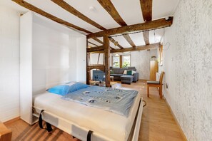 Un dormitorio con cama, vigas de madera, un sofá y una silla.