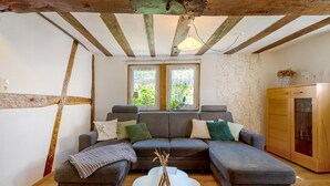 A modern living room with a grey sectional sofa, a white coffee table, and a wooden cabinet. - Holiday Home 'Ferienhäuschen Kleine Auszeit' with Private Terrace, Private Garden and Wi-Fi (Seesbach)