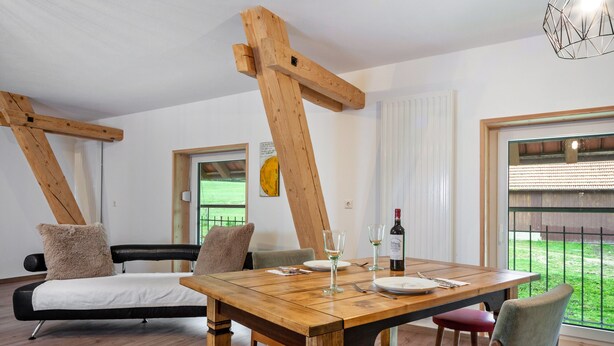 Ein Essbereich mit Holztisch, Stühlen und Blick ins Freie.