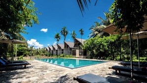A swimming pool with lounge chairs and palm trees. - Lavendish Wild Wilpattu (Nochchiyagama)