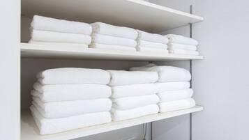 A white shelf with neatly folded white towels.