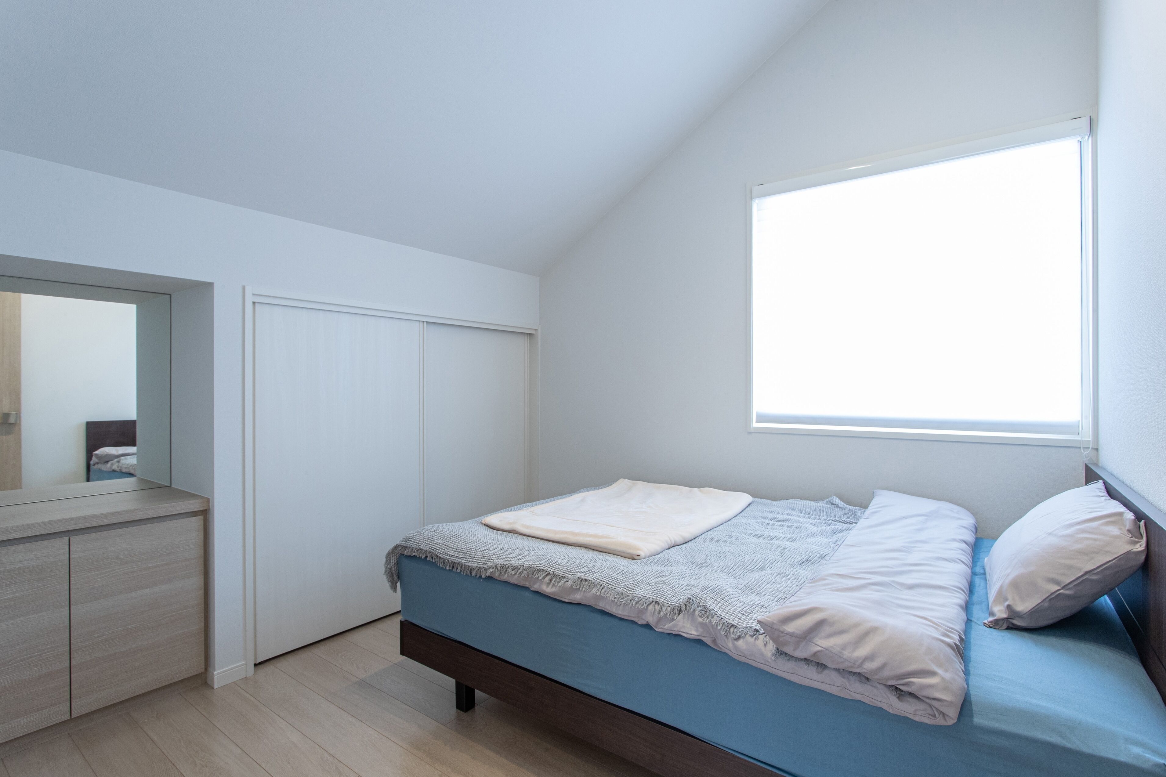 A bedroom with a bed, a dresser, and a window.