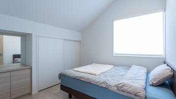 A bedroom with a bed, a dresser, and a window.