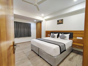 A bedroom with a bed, wooden headboard, and a ceiling fan. - BKR Grand Hotel (Tirupati)
