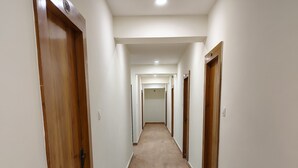 Pitkä, kapea käytävä, jonka molemmilla puolilla on puiset ovet, ja joka johtaa huoneeseen käytävän päässä.