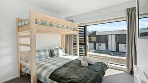 A bunk bed with a checkered bedspread, a green blanket, and a rolled towel. - Mt Roy Delight (Wānaka)
