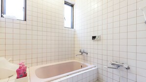 A bathroom with a bathtub, a window, and a shower control panel. - Eat and live like locals (Shinagawa City)