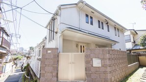 A two-story residential building with a gated entrance, stone pathway, and a brick wall. - Eat and live like locals (Shinagawa City)